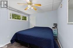 Bedroom with dark hardwood / wood-style flooring, wooden walls, and ceiling fan - 