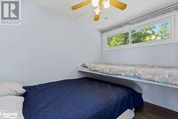 Bedroom featuring dark wood-type flooring, ceiling fan, and wooden walls - 