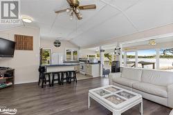 Living room featuring dark wood-type flooring, vaulted ceiling, and ceiling fan - 