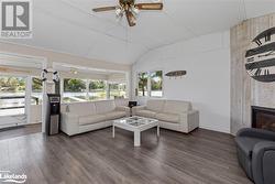 Living room with wood-type flooring, ceiling fan, lofted ceiling, and a tile fireplace - 