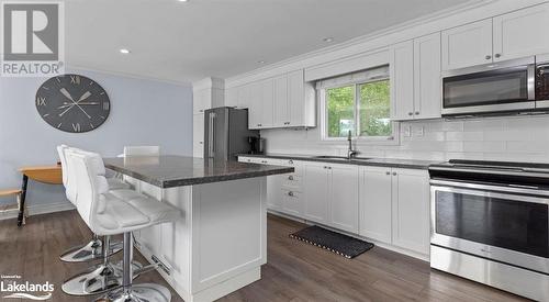 Kitchen with stainless steel appliances, sink, a kitchen island, a breakfast bar, and white cabinetry - 64 Wolverine Beach Road, Port Severn, ON - Indoor Photo Showing Kitchen With Double Sink With Upgraded Kitchen