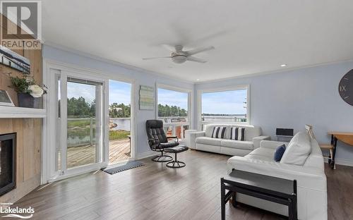 Living room featuring dark wood-type flooring and a wealth of natural light - 64 Wolverine Beach Road, Port Severn, ON - Indoor Photo Showing Living Room With Fireplace