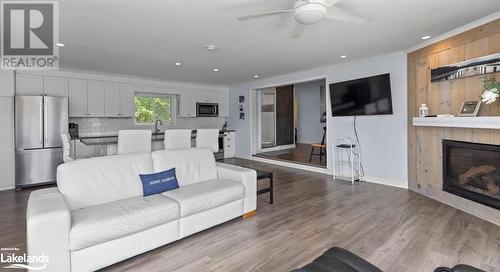 Living room with light wood-type flooring, a tiled fireplace, ceiling fan, and crown molding - 64 Wolverine Beach Road, Port Severn, ON - Indoor Photo Showing Living Room With Fireplace