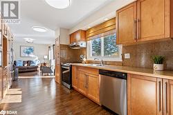 Kitchen with decorative backsplash, appliances with stainless steel finishes, dark hardwood / wood-style floors, and sink - 