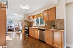 Kitchen featuring stainless steel appliances, sink, tasteful backsplash, and dark hardwood / wood-style flooring - 