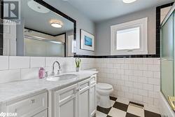 Full bathroom with shower / bath combination with glass door, vanity, toilet, and tile walls - 