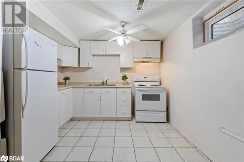 Kitchen featuring sink, a textured ceiling, light tile patterned floors, white appliances, and white cabinets - 2604 Homelands Drive, Mississauga, ON - Indoor Photo Showing Kitchen With Double Sink