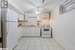 Kitchen featuring sink, a textured ceiling, light tile patterned floors, white appliances, and white cabinets - 