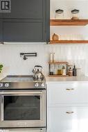 Kitchen with decorative backsplash and stainless steel range with electric stovetop - 