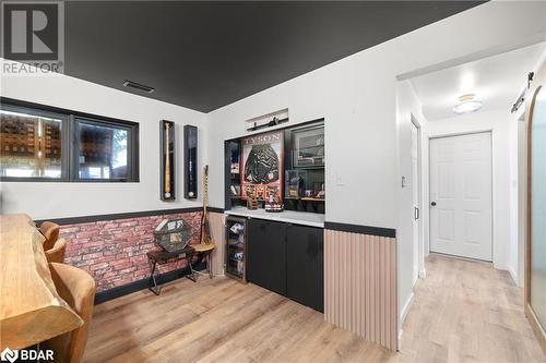 Bar featuring light hardwood / wood-style floors, brick wall, a barn door, and beverage cooler - 18133 Loyalist Parkway, Prince Edward County, ON - Indoor Photo Showing Other Room