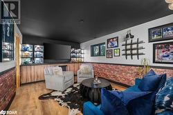 Living room featuring light hardwood / wood-style flooring, bar, and brick wall - 