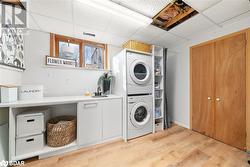 Laundry room featuring light wood-type flooring, cabinets, stacked washer / drying machine, and sink - 