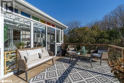 Wooden deck featuring an outdoor living space and a sunroom - 