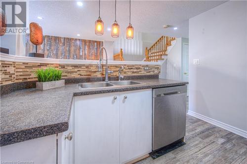 Kitchen with white cabinetry, a textured ceiling, stainless steel dishwasher, and backsplash - 83 Bridlewreath Street, Kitchener, ON - Indoor Photo Showing Kitchen With Double Sink