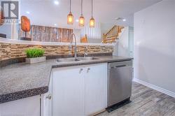 Kitchen with white cabinetry, a textured ceiling, stainless steel dishwasher, and backsplash - 