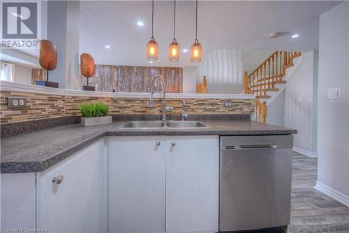 Kitchen with dishwasher, decorative backsplash, white cabinets, sink, and pendant lighting - 83 Bridlewreath Street, Kitchener, ON - Indoor Photo Showing Kitchen With Double Sink