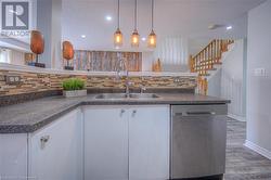 Kitchen with dishwasher, decorative backsplash, white cabinets, sink, and pendant lighting - 