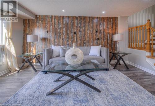 Living area featuring hardwood / wood-style floors, wood walls, and a textured ceiling - 83 Bridlewreath Street, Kitchener, ON - Indoor Photo Showing Living Room