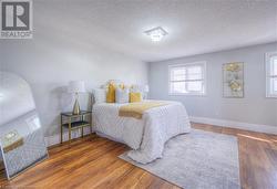 Bedroom with a textured ceiling, dark hardwood / wood-style flooring, and multiple windows - 