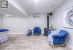 Sitting room with a wood stove, light hardwood / wood-style floors, and a textured ceiling - 