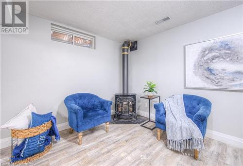 Living area featuring wood-type flooring, a textured ceiling, and a wood stove - 83 Bridlewreath Street, Kitchener, ON - Indoor Photo Showing Other Room