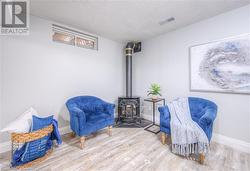 Living area featuring wood-type flooring, a textured ceiling, and a wood stove - 