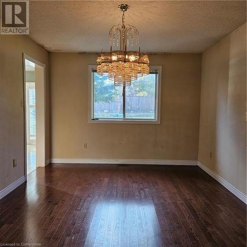 Unfurnished dining area featuring dark hardwood / wood-style flooring, a notable chandelier, and a textured ceiling - 115 Cranston Avenue, Cambridge, ON - Indoor Photo Showing Other Room