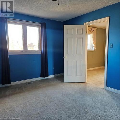 Unfurnished bedroom with a textured ceiling and light carpet - 115 Cranston Avenue, Cambridge, ON - Indoor