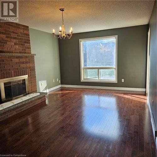 Unfurnished living room with a fireplace, hardwood / wood-style floors, and a textured ceiling - 115 Cranston Avenue, Cambridge, ON - Indoor With Fireplace