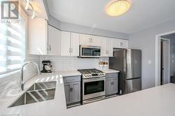 Kitchen featuring a wealth of natural light, appliances with stainless steel finishes, sink, and gray cabinetry - 