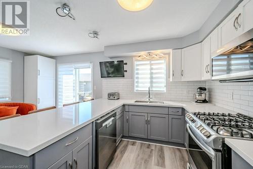 Kitchen with light wood-type flooring, appliances with stainless steel finishes, gray cabinets, sink, and kitchen peninsula - 192 Severn Drive, Guelph, ON - Indoor Photo Showing Kitchen With Upgraded Kitchen