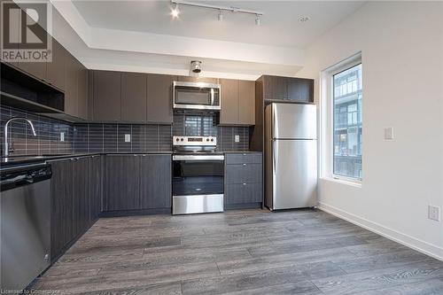 Kitchen with light wood-type flooring, appliances with stainless steel finishes, decorative backsplash, and sink - 1095 Cooke Boulevard Unit# 42, Burlington, ON - Indoor Photo Showing Kitchen With Stainless Steel Kitchen