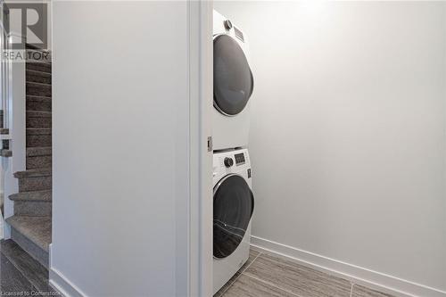 Washroom featuring dark wood-type flooring and stacked washing maching and dryer - 1095 Cooke Boulevard Unit# 42, Burlington, ON - Indoor Photo Showing Laundry Room