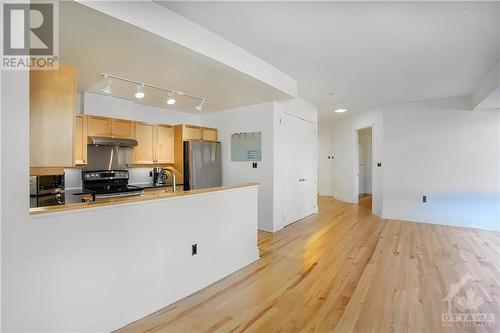 Digitally staged image showcasing the living room's open view into the kitchen, illustrating the spacious and seamless flow between areas. - 364 Cooper Street Unit#403, Ottawa, ON - Indoor Photo Showing Kitchen