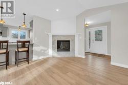 Living room with lofted ceiling, a wealth of natural light, a high end fireplace, and light hardwood / wood-style flooring - 