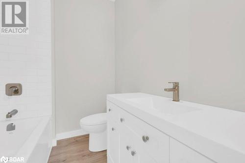 Full bathroom featuring wood-type flooring, vanity, toilet, and tiled shower / bath - 530 Addington Road 5, Cloyne, ON - Indoor Photo Showing Bathroom