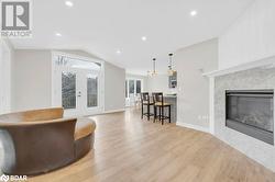 Living room featuring french doors, vaulted ceiling, a premium fireplace, and light hardwood / wood-style flooring - 