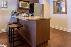 Kitchen with backsplash, appliances with stainless steel finishes, dark hardwood / wood-style floors, a kitchen breakfast bar, and kitchen peninsula - 