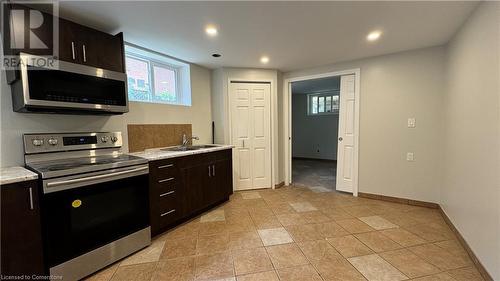 Kitchen featuring light stone countertops, dark brown cabinets, sink, and appliances with stainless steel finishes - 406 Erb Street W Unit# 2, Waterloo, ON - Indoor Photo Showing Kitchen