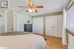 Bedroom featuring multiple closets, light wood-type flooring, a textured ceiling, and ceiling fan - 