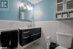 Bathroom featuring vanity, toilet, and tile walls - 