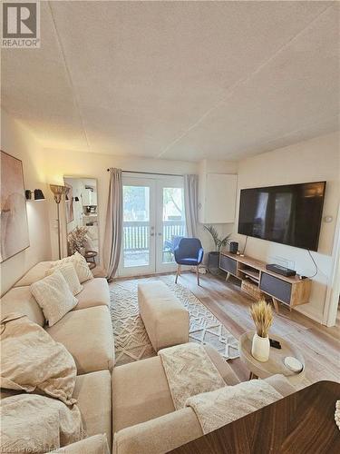 Living room featuring a textured ceiling, light hardwood / wood-style flooring, and french doors - 2030 Cleaver Avenue Unit# 122, Burlington, ON - Indoor Photo Showing Living Room