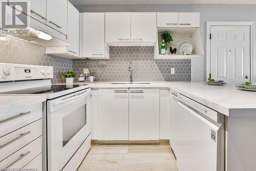 Kitchen featuring white cabinetry, decorative backsplash, sink, white appliances, and light hardwood / wood-style flooring - 2030 Cleaver Avenue Unit# 122, Burlington, ON - Indoor Photo Showing Kitchen