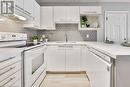 Kitchen featuring white cabinetry, decorative backsplash, sink, white appliances, and light hardwood / wood-style flooring - 2030 Cleaver Avenue Unit# 122, Burlington, ON  - Indoor Photo Showing Kitchen 