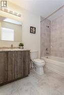 Full bathroom with vanity, tiled shower / bath, and toilet - 