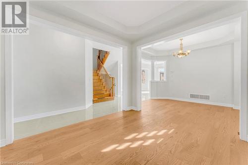 Empty room featuring light wood-type flooring, a notable chandelier, and a raised ceiling - 1174 Upper Thames Drive, Woodstock, ON - Indoor Photo Showing Other Room