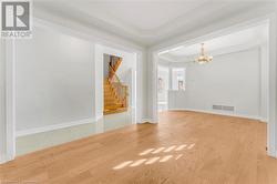 Empty room featuring light wood-type flooring, a notable chandelier, and a raised ceiling - 