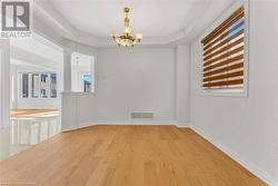 Spare room featuring light hardwood / wood-style flooring, a tray ceiling, decorative columns, and an inviting chandelier - 