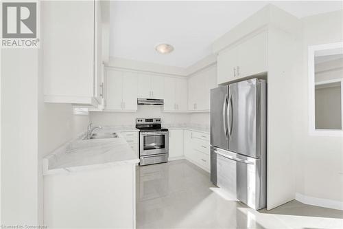 Kitchen with white cabinets, stainless steel appliances, sink, and light tile patterned floors - 1174 Upper Thames Drive, Woodstock, ON - Indoor Photo Showing Kitchen With Stainless Steel Kitchen