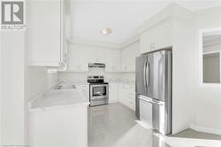 Kitchen with white cabinets, stainless steel appliances, sink, and light tile patterned floors - 